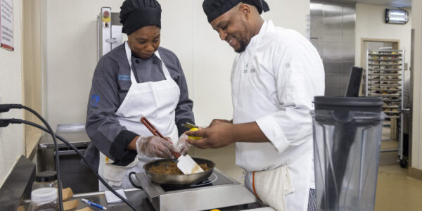 Teacher and student of the Culinary program cook a meal together in the kitchen