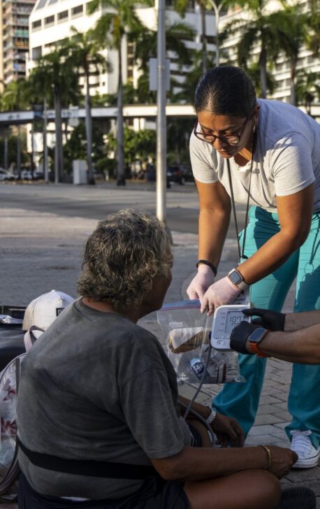 Nurse giving medical aid to homeless individual on the street.